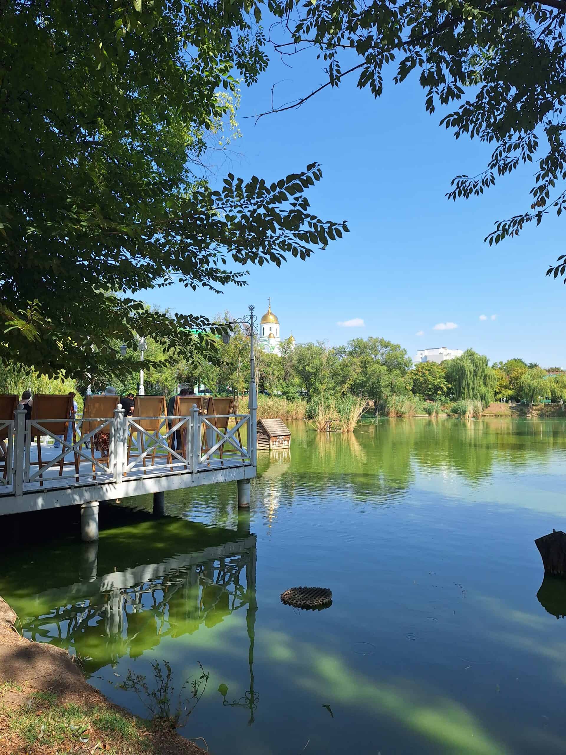 Entspannter See in Transnistrien im Park mit Wasser, Bäumen und einem Steg, ideal für Spaziergänge.